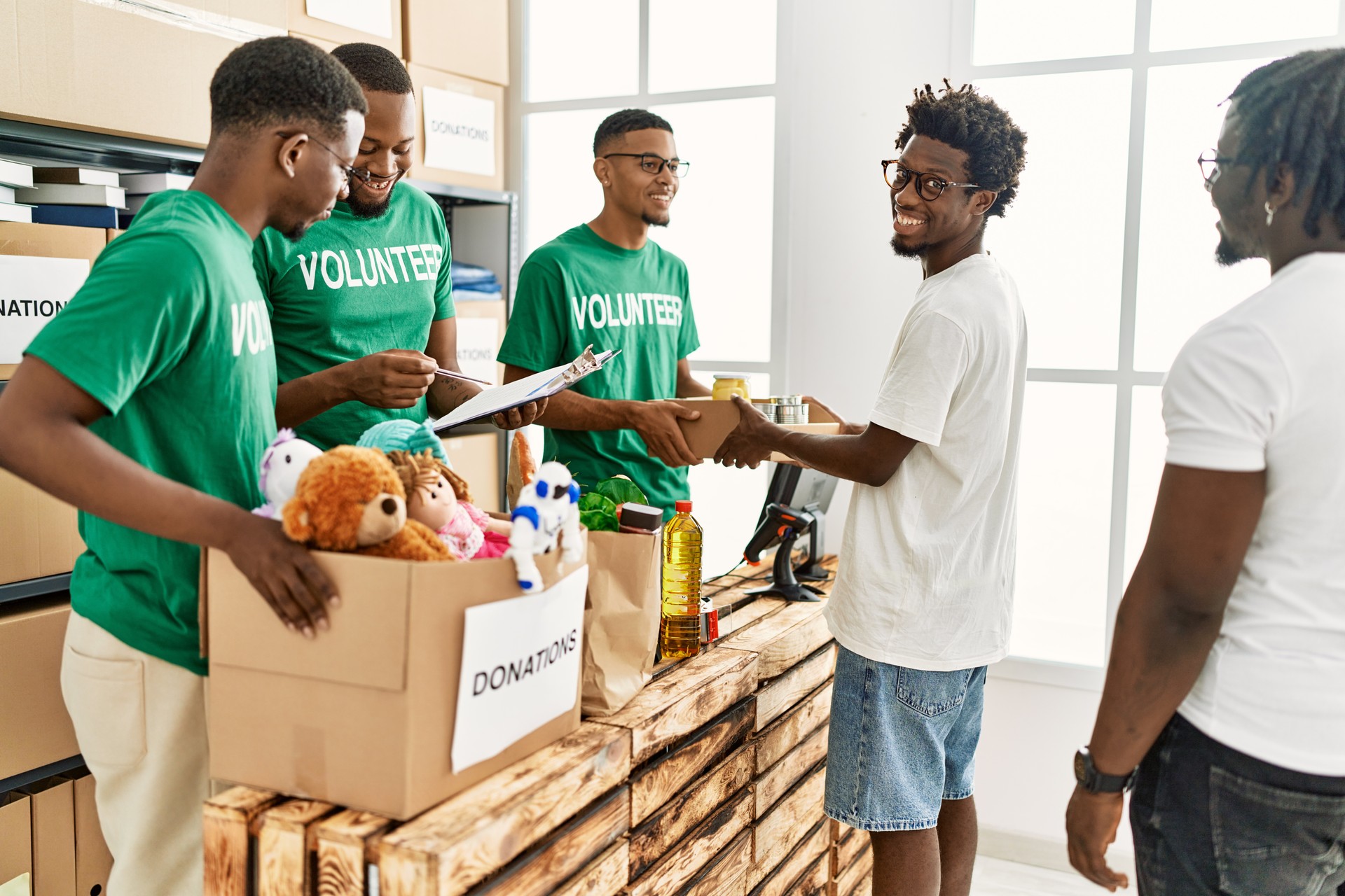 Group of young african american volunteers helping people at charity center.