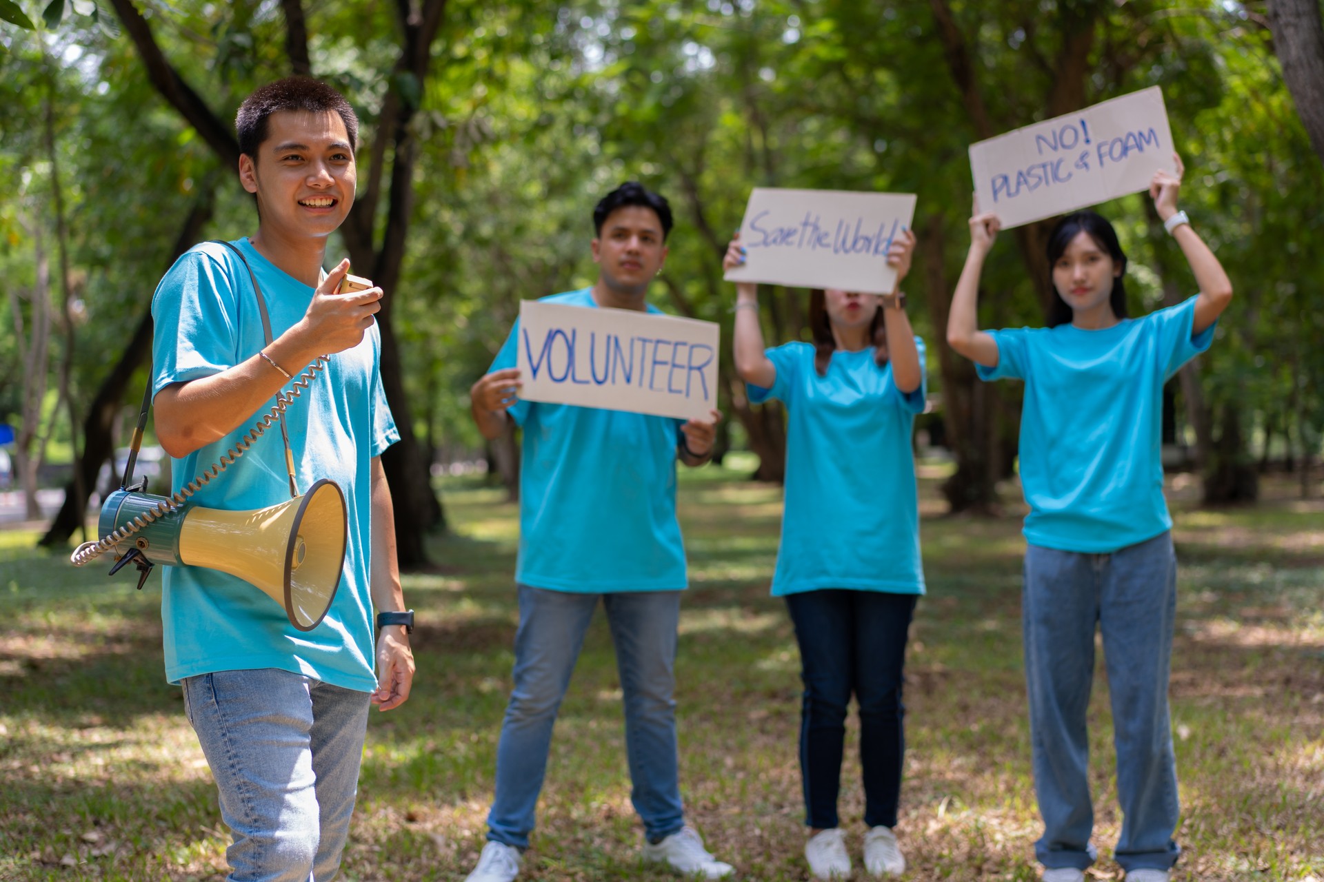 Happy young Asian students diverse volunteers hold a campaign sign for cleaning in the park, The concept of environmental conservation on world environment day, recycling, charity for sustainability.